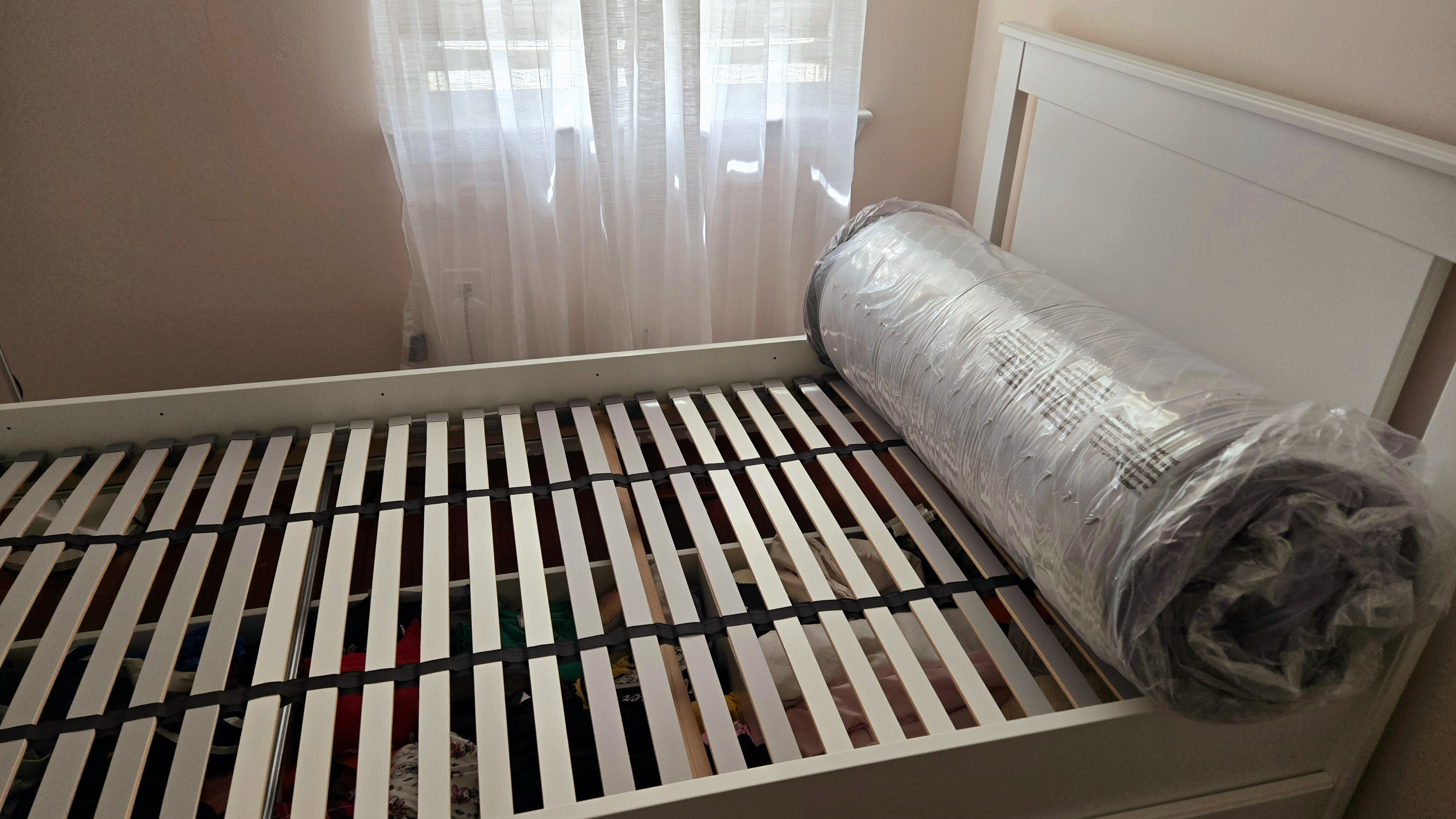 Siena Premier Hybrid Mattress wrapped in plastic on our tester's slatted bed during setup