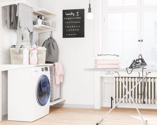 A laundry room with ironing board and washing machine