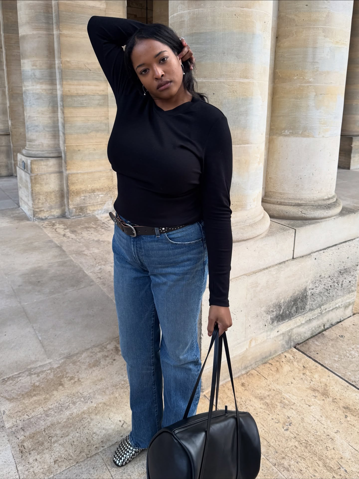 Woman wearing a black long-sleeve and blue jeans.