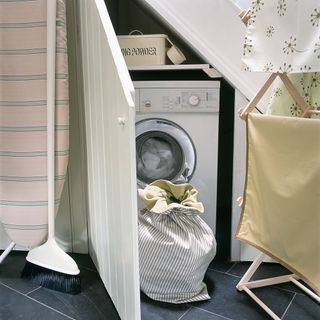 white washing machine with clothes rack and dark flooring