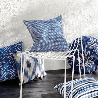 white metal chair with blue cushion and white textured wall