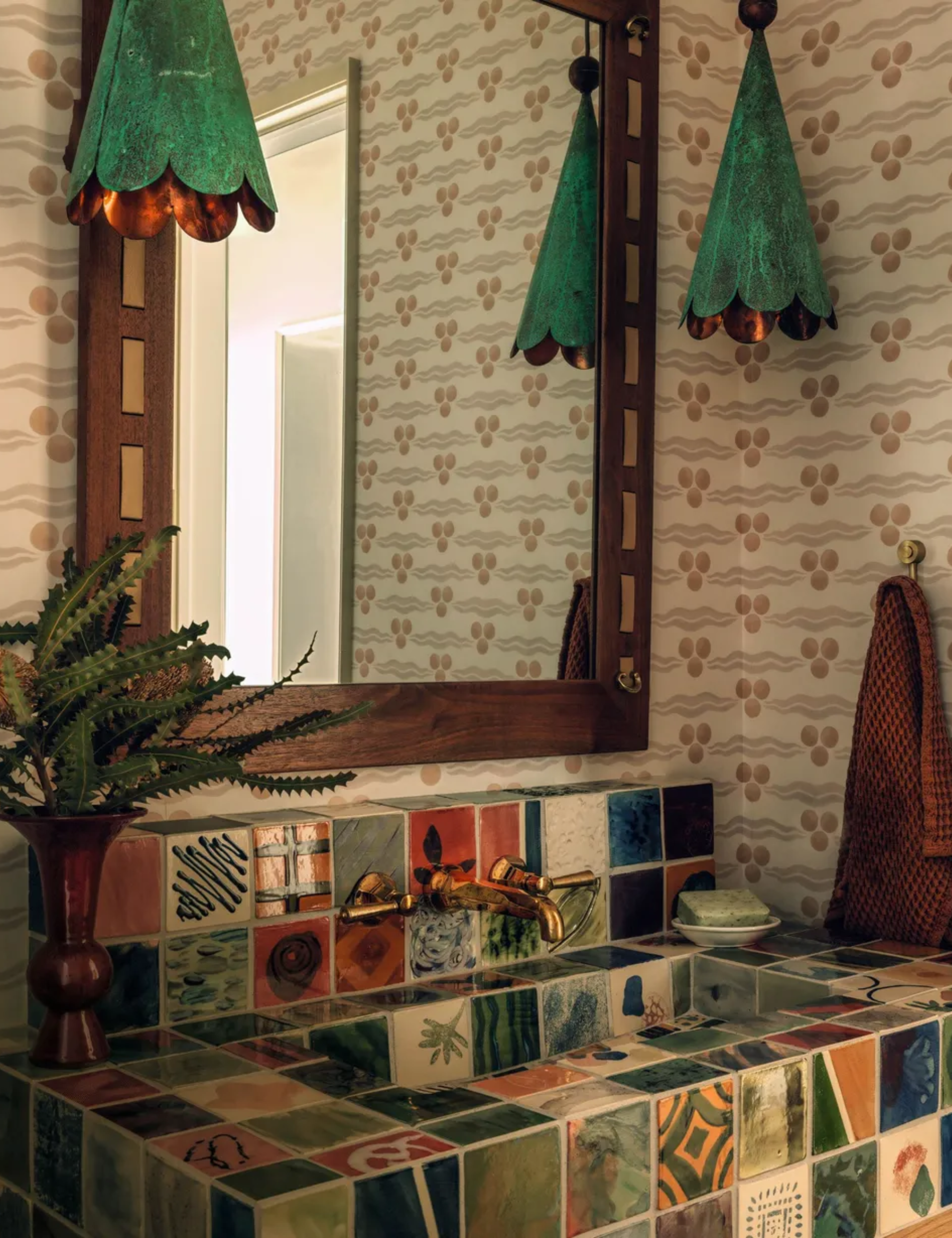 Powder room with statement tiled sink, wooden mirror, green pendant lights and patterned wallpaper