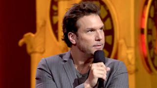 A still of Dane Cook performing stand-up.