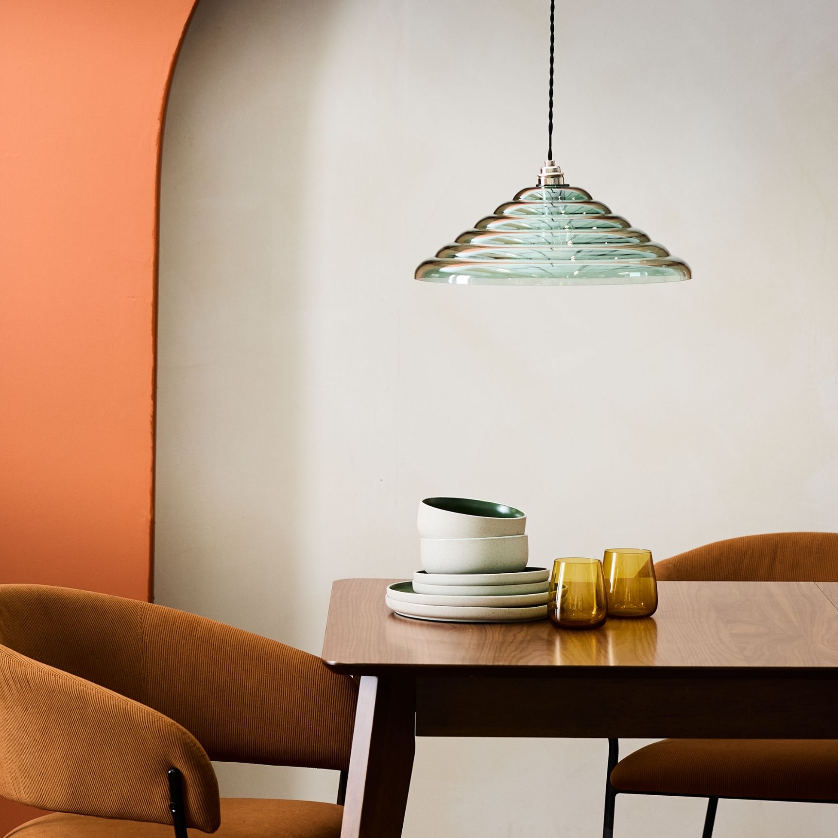 a dining table with a glass lampshade above