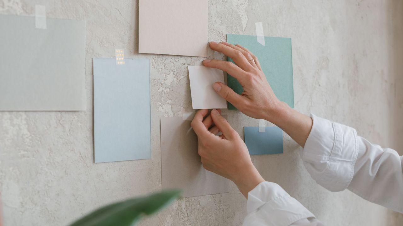 Somone sticking paint samples to a plaster wall