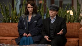 From left to right: Rachel Brosnahan and Alex Borstein sitting next to each other on a couch on The Marvelous Mrs. Maisel.