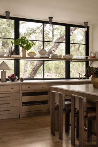 A wood-lined kitchen with a simple wooden shelf stretching across a large window