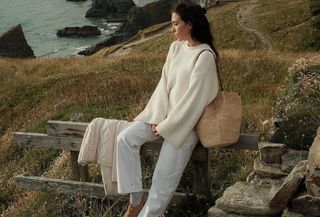 Jessica wears an ivory sweater, white jeans, tan clogs, and a straw shoulder bag.