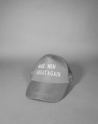 Black and white photo of peak cap with the words "MAKE MEN GREAT AGAIN" on.