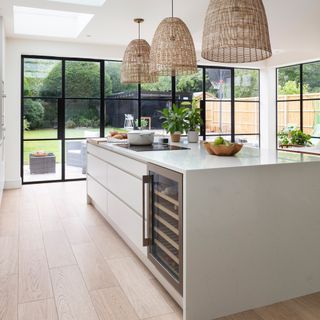 Scandi-style white kitchen with wine fridge and large oversized pendants