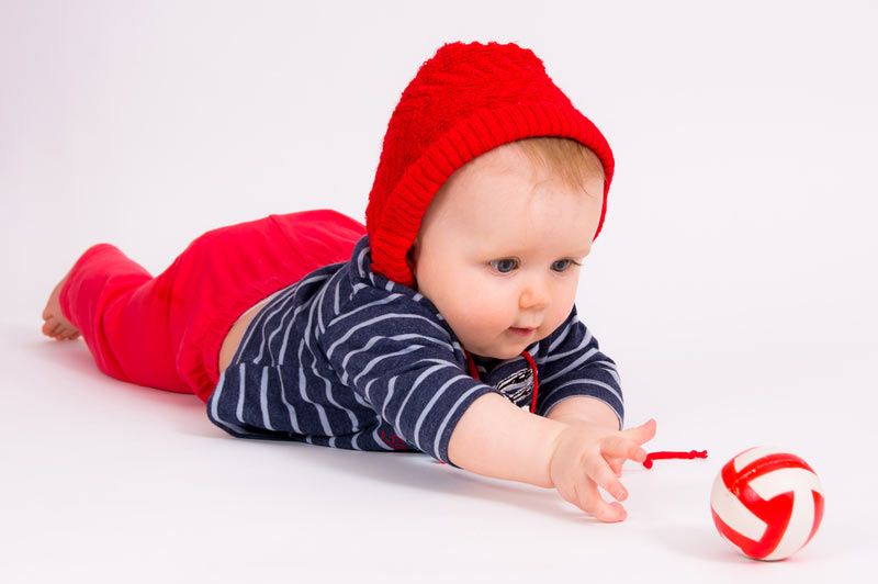 young baby playing with a red ball