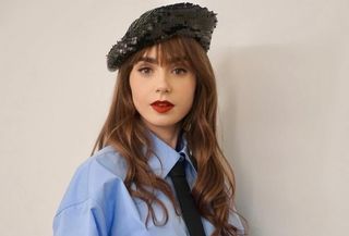 Lily Collins wearing a sequin beret with a Valentino blue shirt and black tie doing press for Emily In Paris season 4.