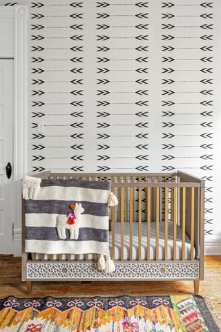 gender neutral office with patterned wallpaper, cot, blanket