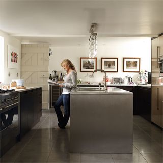 Women in kitchen with white walls black cabninet