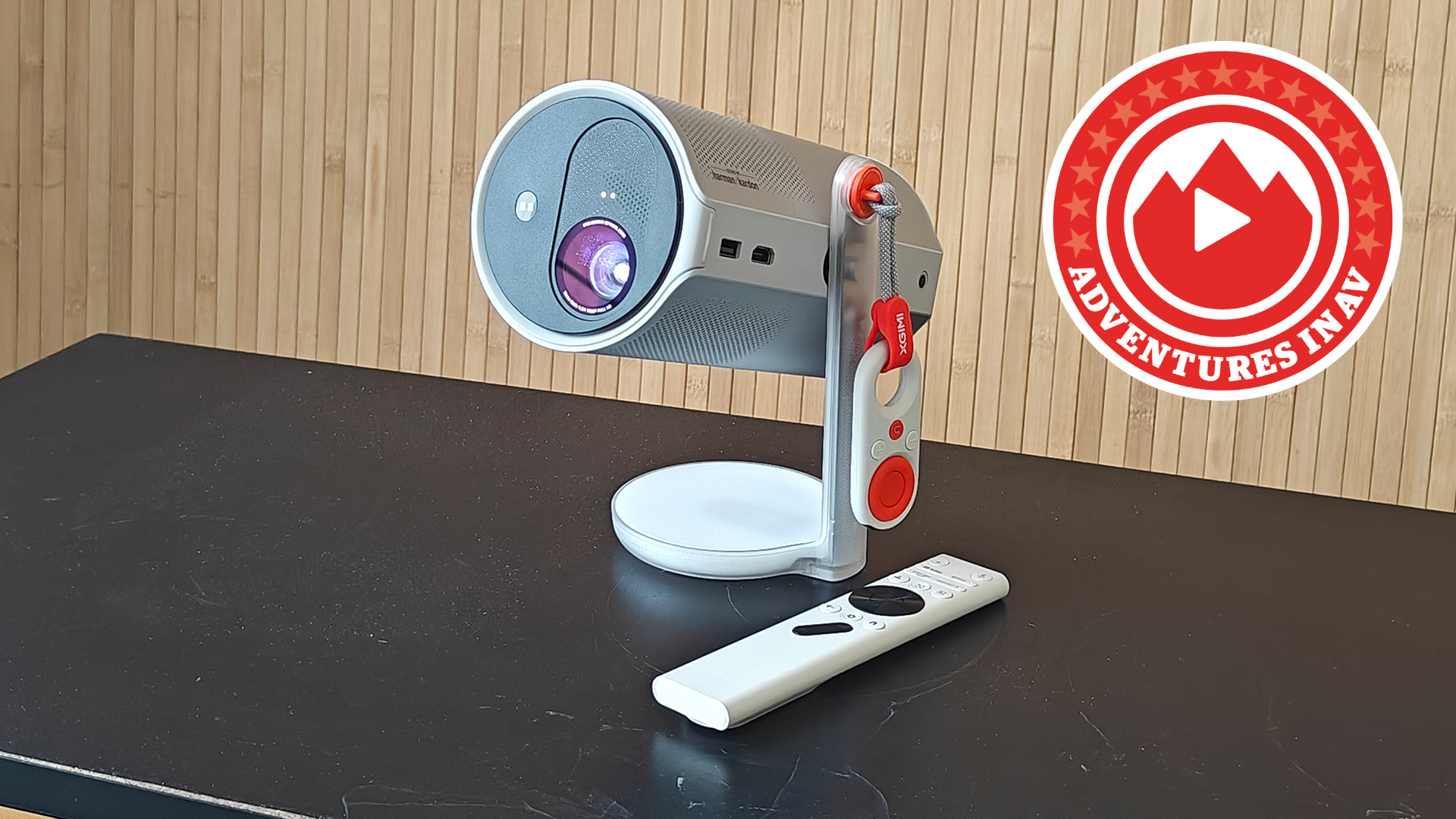 Xgimi MoGO 4 projector on a black surface with a wooden background, with a logo that says "Adventures in AV"