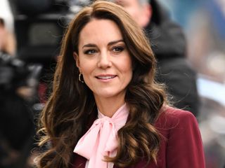 Kate Middleton wears a burgundy blazer and a pink pussy-bow blouse