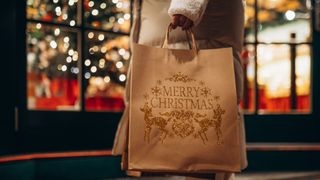 Hand holding Christmas shopping bags against the background of festive storefront.