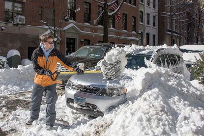A man clears his car in New York City after a weekend of blizzards