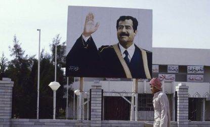 Saddam Hussein's military protection may have saved him from an uprising, were he in power today. An Iraqi passes Saddam propaganda in the late 1980s.