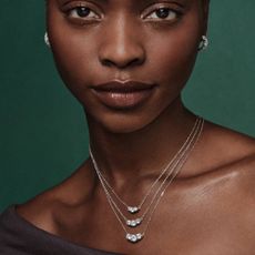 A woman wearing three silver, diamond-layered necklaces from Jared. 