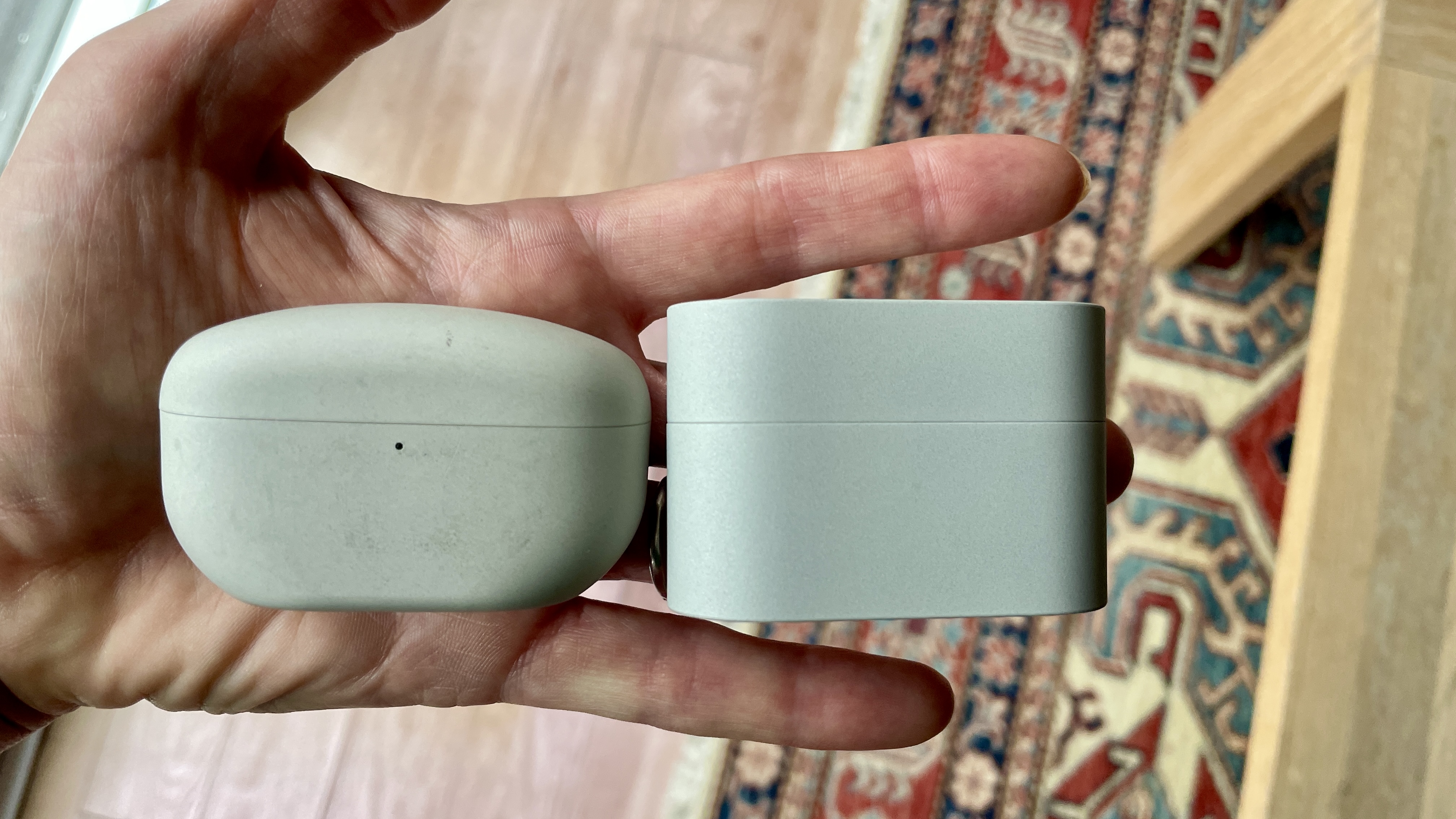 The Sony WF-10000XM6 next to the Sony WF-1000XM5, held in a hand, to show the size difference 