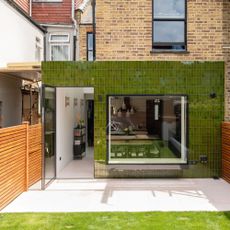 extending into the side return the exterior of a house covered in green tiled cladding