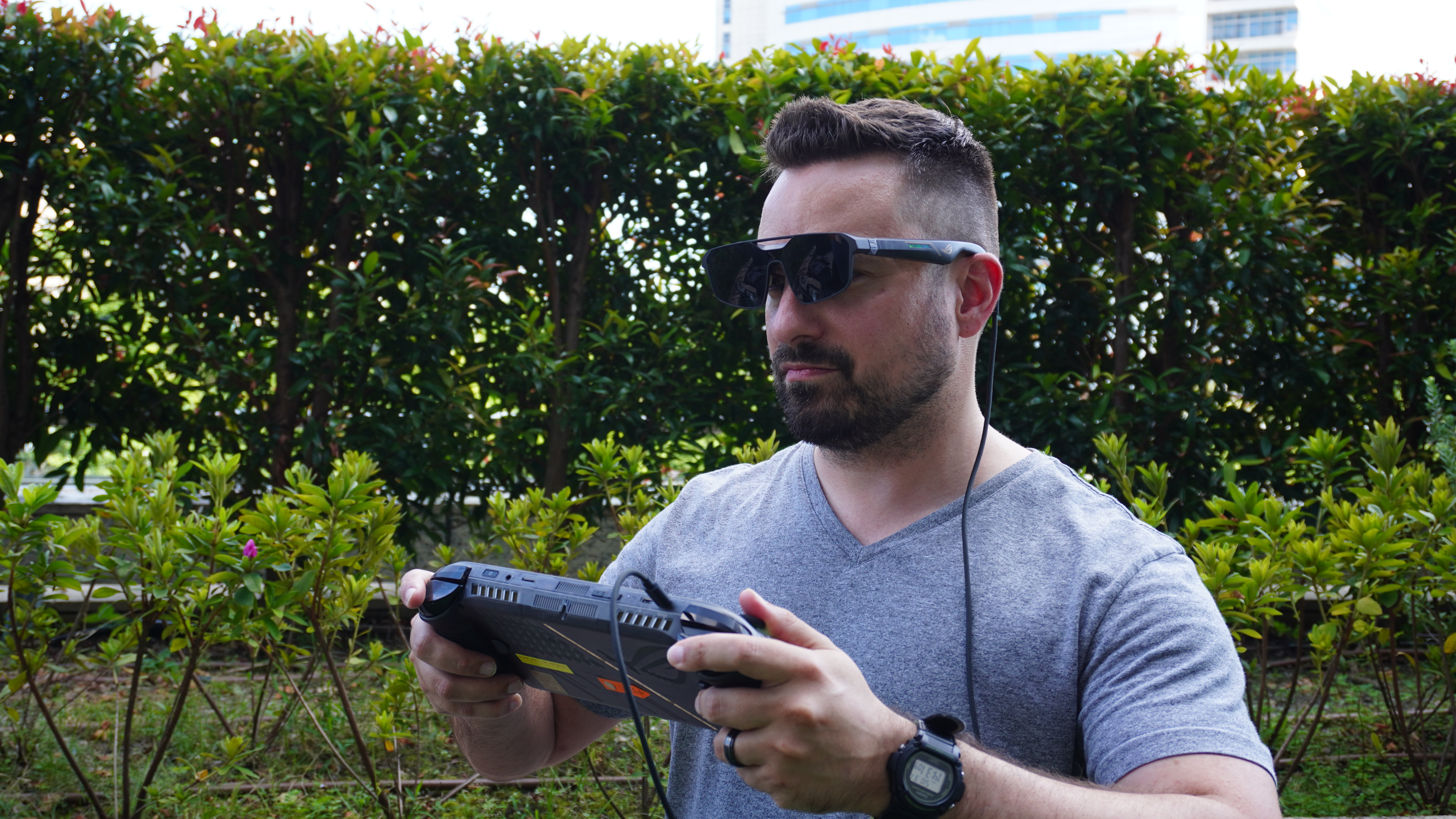 A person playing the Asus ROG Xbox Ally X20 while wearing smart glasses