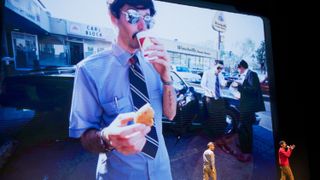 A still from the Beastie Boys Story, with AdRock and Mike D talking in front of an image of MCA from the Sabotage video