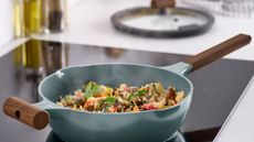 Turquoise pan with wood handles, on induction stovetop