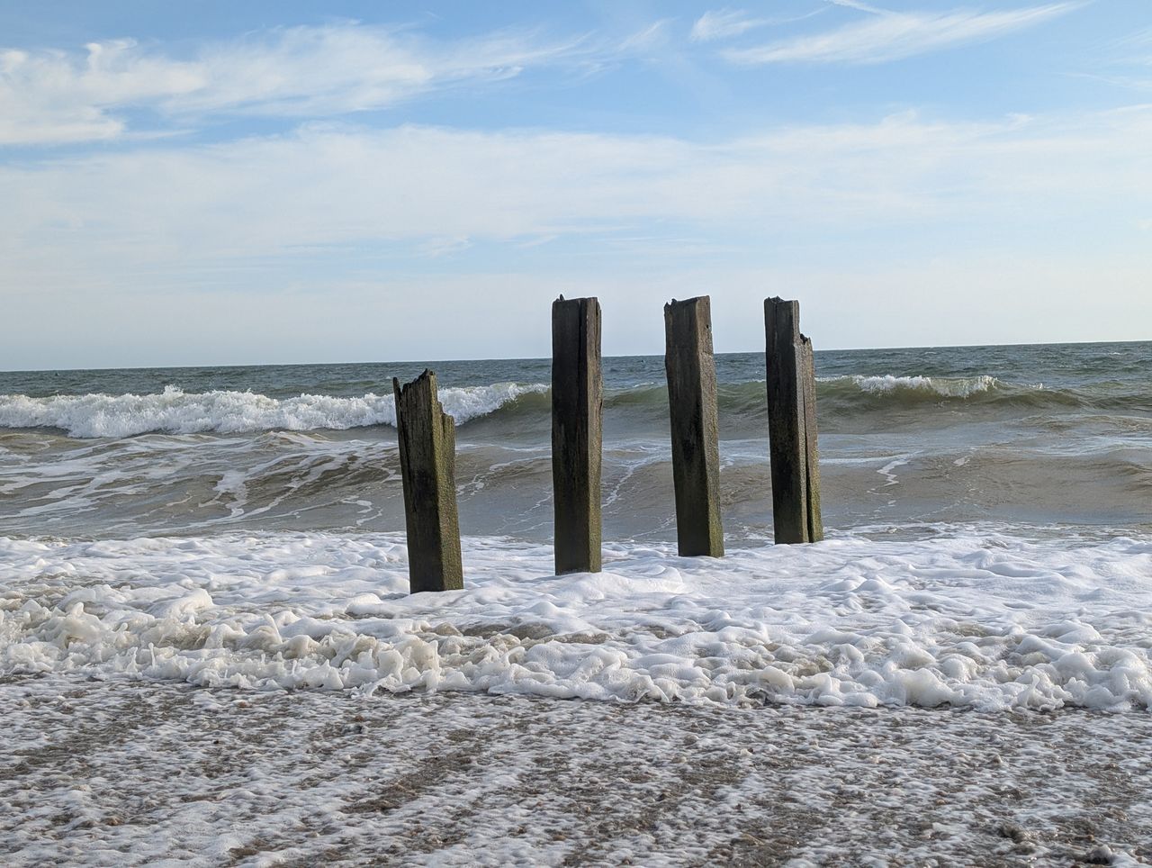 A damaged groyne on a UK beach, the high tide is smashing into it