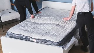 Two testers feeling a mattress that's off-gassing that they've just unboxed