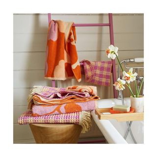 Patterned towels in colorful pops - in stack on stool, and hanging on pink towel ladder.
