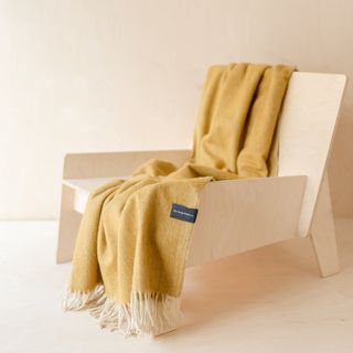 Recycled Wool Small Blanket in Mustard Herringbone draped over wooden chair
