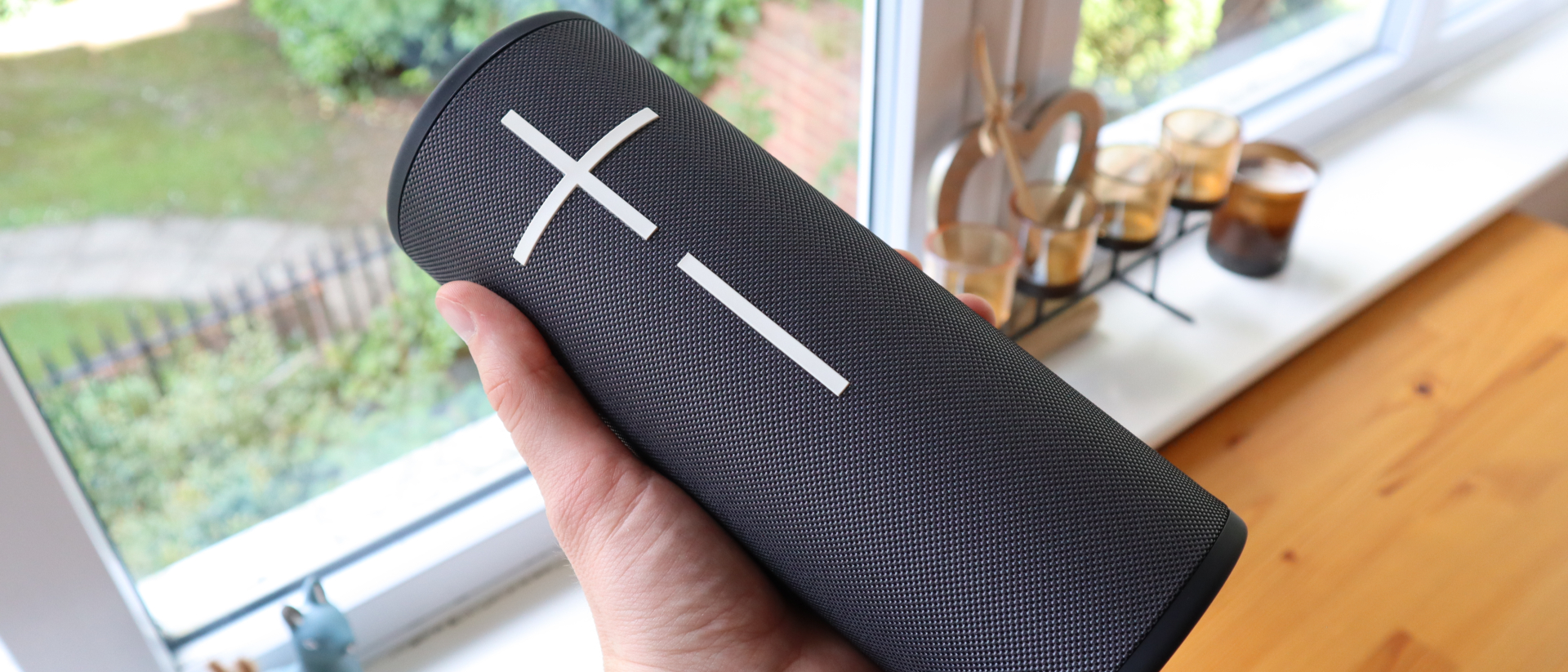 Ultimate Ears Megaboom 4 held in a hand, in front of a window