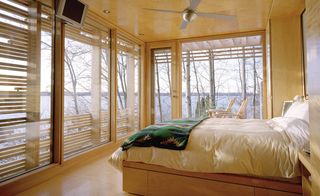 Sunset cabin bedroom with double bed and view of water through glass windows