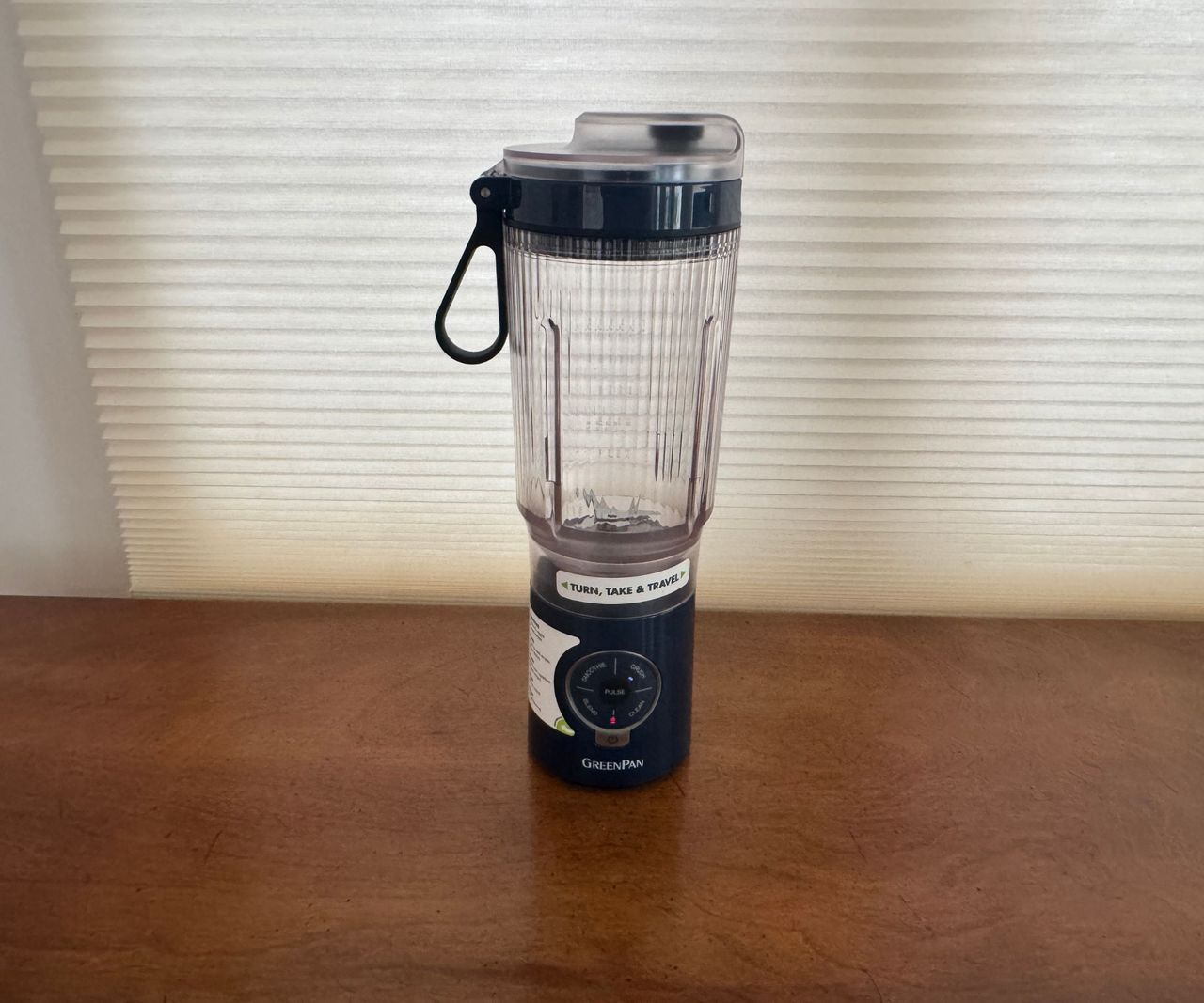 A black based the GreenPan Spin &amp; Go portable blender on a wooden table.