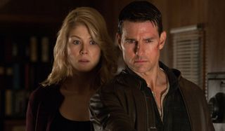 Tom Cruise holds someone at gunpoint while Rosamund Pike watches in Jack Reacher.