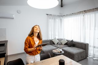 Eine Frau steuert ihre Wohnzimmerbeleuchtung via Tablet