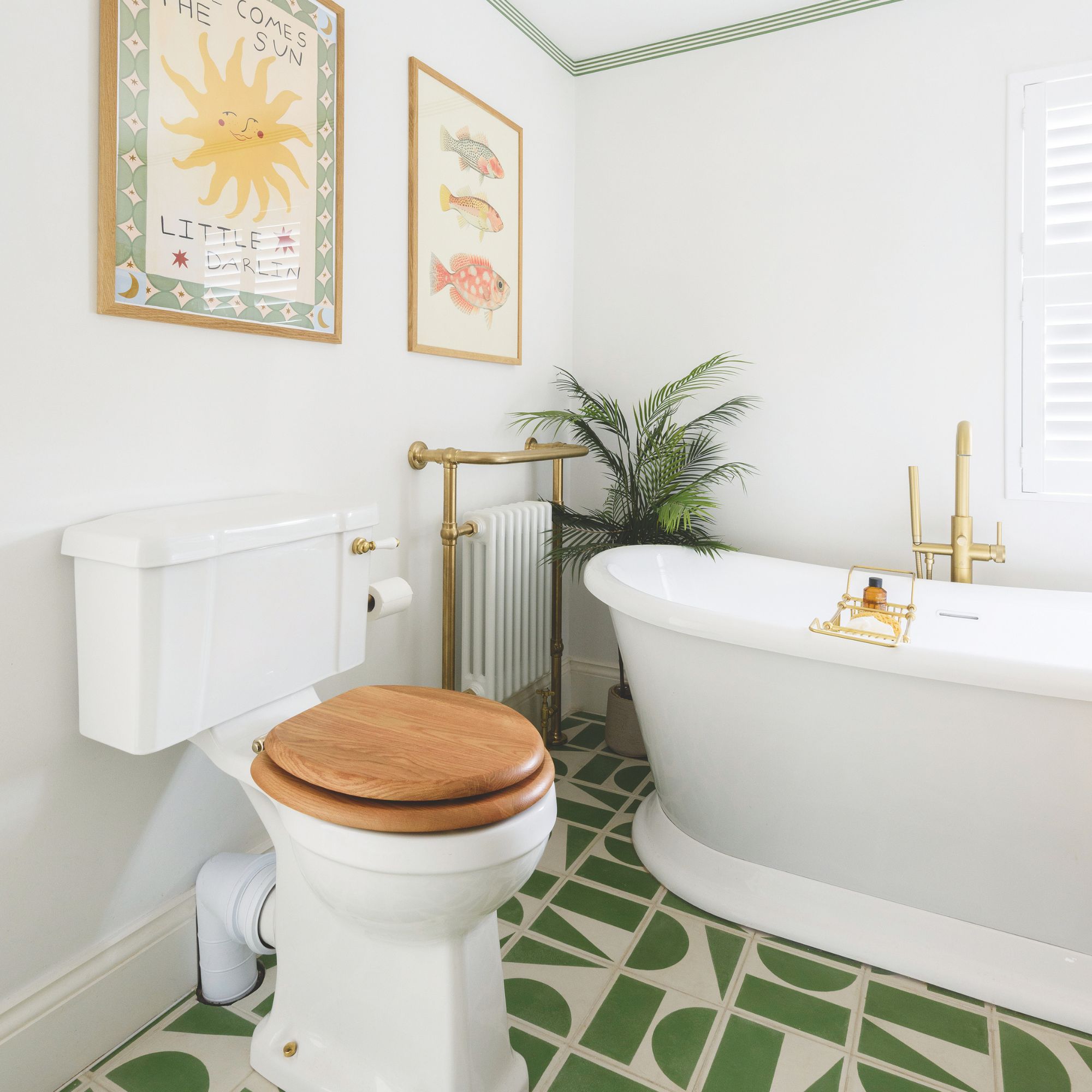 White painted bathroom with a freestanding bath, toilet with wooden seat, and green and white patterned tiles