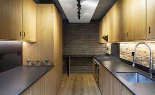 long kitchen out of wood in Southwark brick house by Satish Jassal