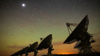 large satellite dishes point upward at the night sky