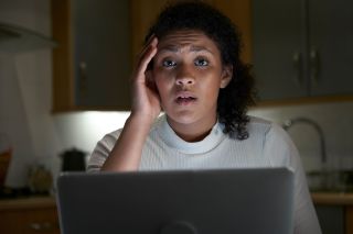 Portrait Of Unhappy Woman At Home With Computer Victim Of Online Crime.