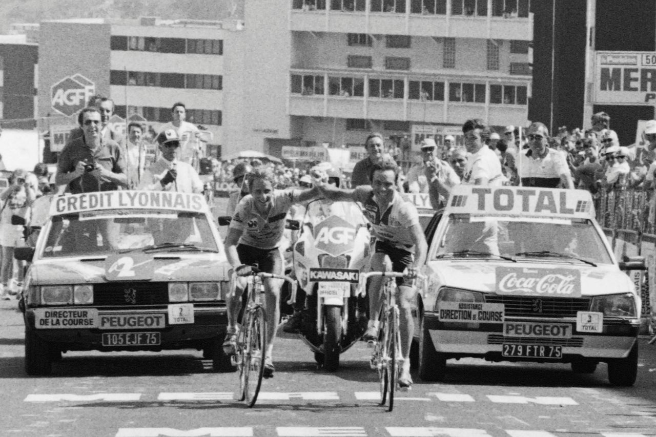 Frenchman Bernard Hinault R and his teammate US Greg Lemond smile as they cross the finish line together at the end of the 18th stage of the Tour de France between Brianon and lAlpe dHuez on July 21 1986 Hinault won the stage and Greg Lemond retained his leaders yellow jersey and went on to win his first Tour de France in Paris becoming the first American to do so FILM AFP PHOTO AFP Photo credit should read AFP via Getty Images