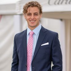 Alexander Ogilvy wearing a navy suit and pink tie and smiling