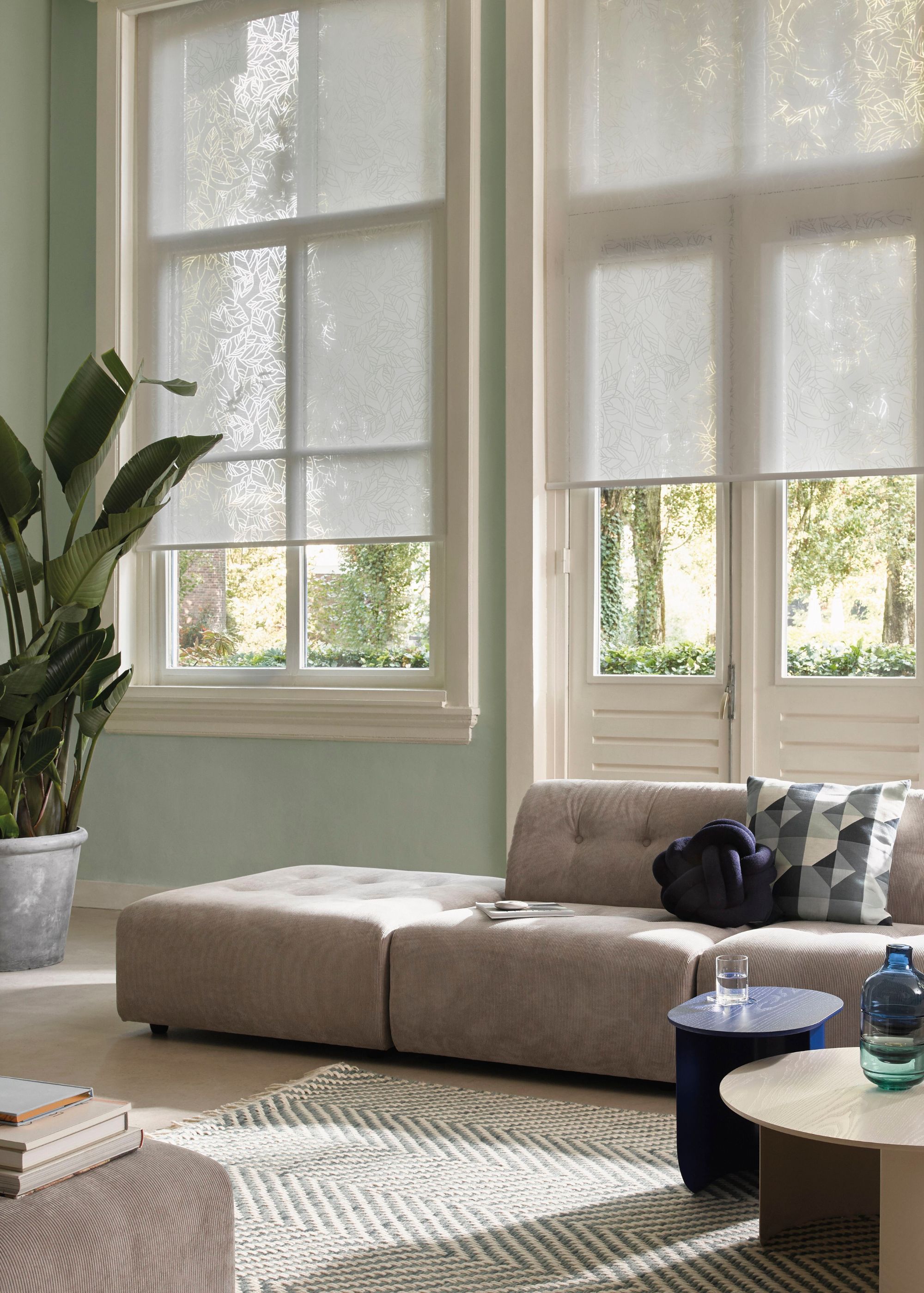 A modern living room with French doors with light gray roller blinds.