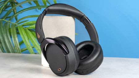 A pair of black Edifier WH950NB over-ear headphones photographed against a blue background