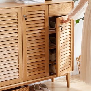 Wooden shoe storage cabinet with hand opening it