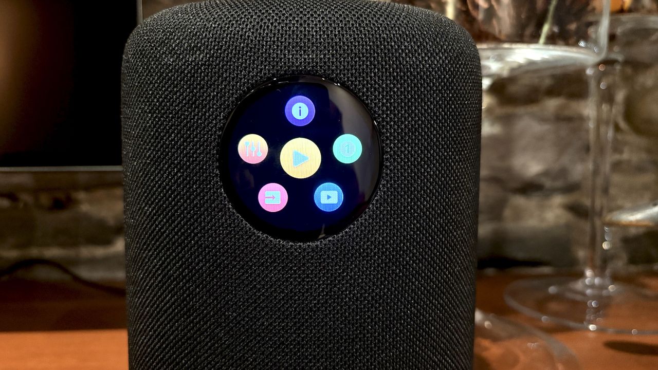 The WiiM Sound, in a home, on a varnished wooden table, showing the illuminated front panel