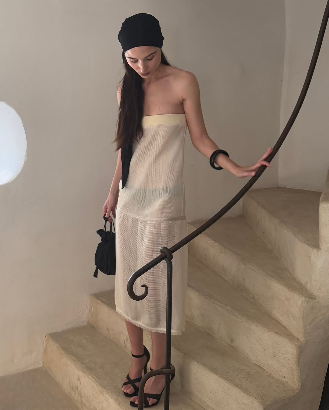 An image of a woman in a sheer white set on the stairs.
