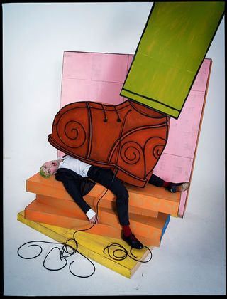 Man lying under a giant cartoon boot